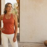 Woman standing outdoors in activewear, hand on hip, in warm light