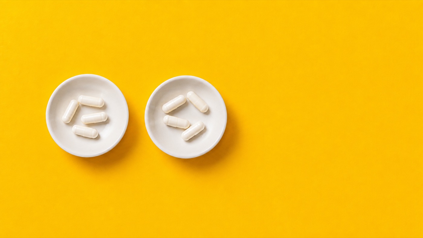 Two small dishes of pale capsules on a bright yellow background