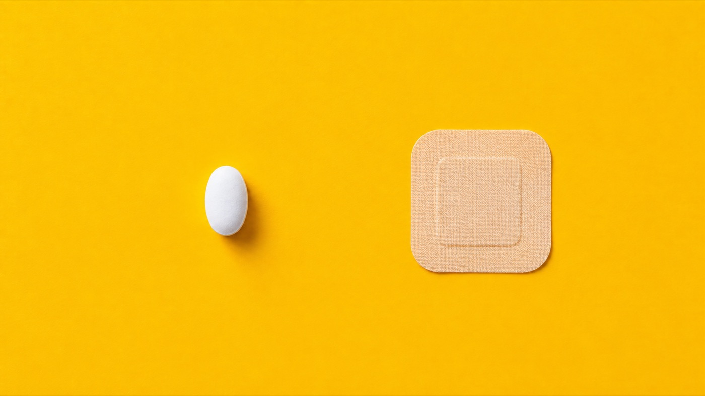A plain white tablet beside a plain skin patch, representing oral and transdermal estrogen