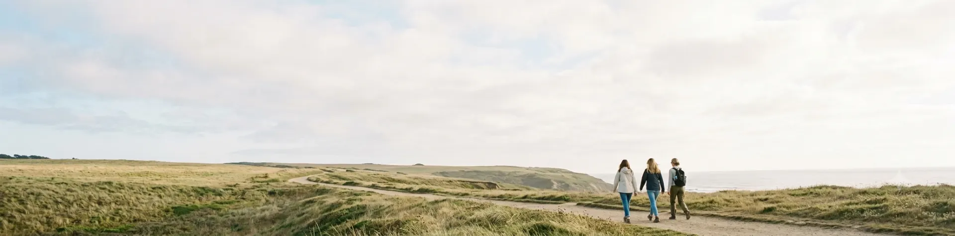 Three women walking a coastal path